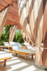 A serene setting at a luxury resort featuring a row of elegant cabanas with flowing drapes and...