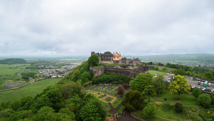 Fototapeta na wymiar A drone view reveals Stirling Castle perched above a vibrant green landscape, with the panoramic Scottish countryside