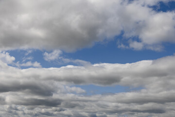 A mesmerizing sky adorned with layers of thick, puffy clouds, offering a glimpse of the azure blue...