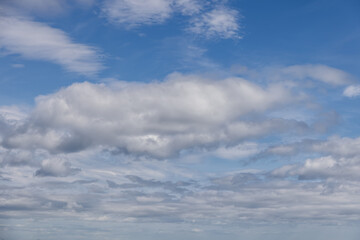 Sky filled with layered clouds drifting lazily over a calm blue backdrop. The soft light filtering...