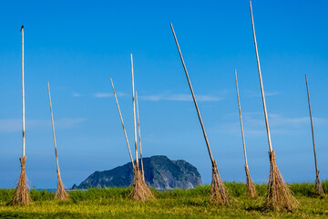 The environmental landscape art in the restoration park of Chaojing , Keelung City, Taiwan, features 12 giant bamboo brooms created by a French artist, overlooking Turtle Island from the green lawn.
