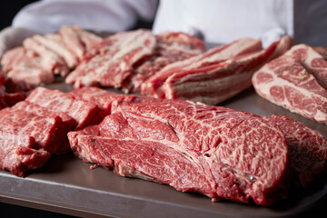 Meat in various parts held by the chef