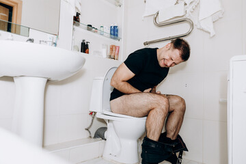 A man is sitting on the toilet with a phone in his hand. Guy's morning routine