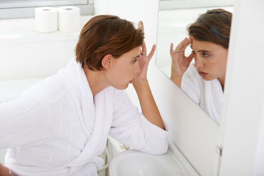 Woman, mirror and headache pain in bathroom for morning sickness or hangover, reflection or fatigue. Female person, hand and nauseous problem for pregnancy in home with bathrobe, migraine or sore