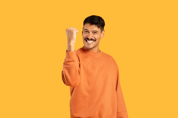 Man with moustache smiling and making a fist