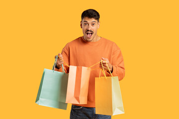 Man excited with shopping bags, solid background