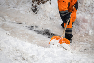 A man with a snow shovel cleans sidewalks in winter.