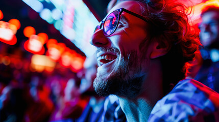 A joyful young man with glasses, enjoying vibrant nightlife ambiance under neon lights, exhibits a...