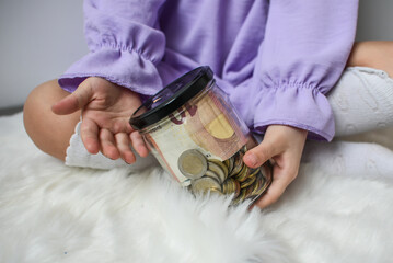 Girl hands holding jar filled with euro coins and banknotes