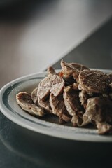 Vertical closeup of cooked meat on a plate.