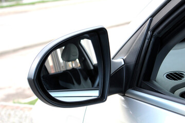 Obraz premium Close-up of the black side mirror of the car. Car mirror with blind spot warning. Car Mirror Cover Rearview Mirror.