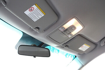 Modern rear view mirror and part of car ceiling. Interior roof car light and ceiling. Sun visors on the car ceiling. Modern car interior.
