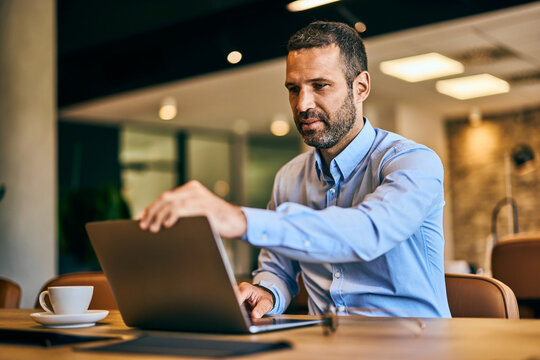 Businessman starting his workday at the office, opening a laptop.