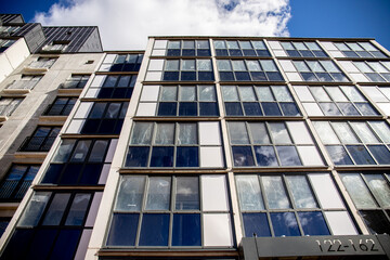 Facade of a high-rise multi-storey residential building decorated with modern materials against the sky. Modern low angle view of building