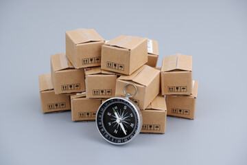 Delivery and shipment concept. Compass and many carton boxes on grey background. 