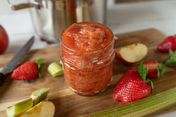 Fresh cooked rhubarb compote with apples and strawberries in a glass jar
