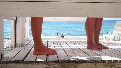 Two woman in the changing, dressing room on beach, at sunset on the seashore. Close-up of bare female feet legs in enclosed changing room cabin. Summer holiday vacation and travel concept. Slow motion