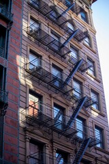 Fototapeta na wymiar Vertical shot of a fire escape staircase of a brick building in New York, United States.
