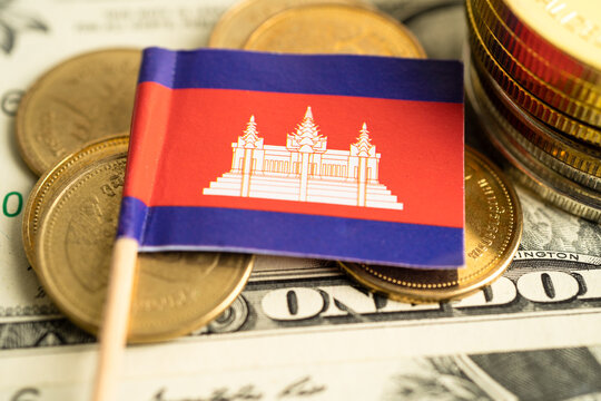 Stack of coins with Cambodia flag and US dollar banknotes.