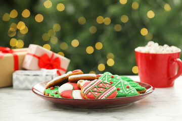 Decorated cookies and hot drink on white marble table against blurred Christmas lights