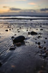 Vertical shot of a beach full of rocks with a calm sea in the background in the evening