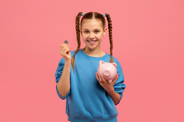 Girl with piggy bank and coin smiling