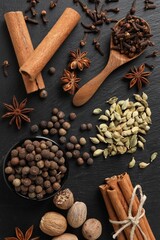 Different spices on black textured table, flat lay