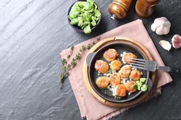 Delicious fried scallops in dish served on dark gray textured table, flat lay. Space for text