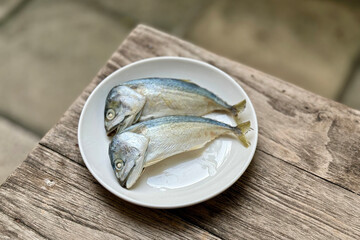 Mackerel fish on the white plate with Wooden Texture table.