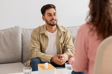 Young man talking to a woman therapist on couch