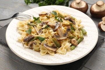 Vegetarian pasta with mushrooms, parsley, string beans and cheese on grey wooden table, closeup