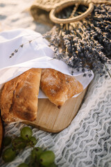 A beautiful picnic: freshly baked fragrant bread and a basket of cut lavender at a golden sunset. vertical photo
