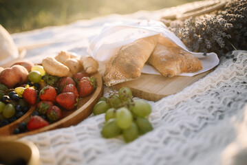 Romantic picnic: Fresh fruits on a wooden plate and fresh ciabatta on the background of the sunset