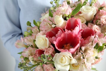 Woman with beautiful bouquet of fresh flowers on light background, closeup