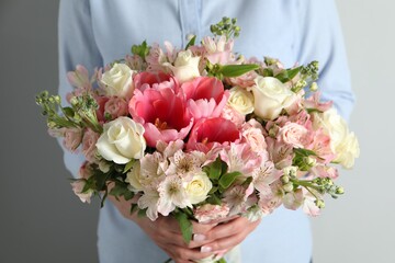 Woman with beautiful bouquet of fresh flowers on light background, closeup