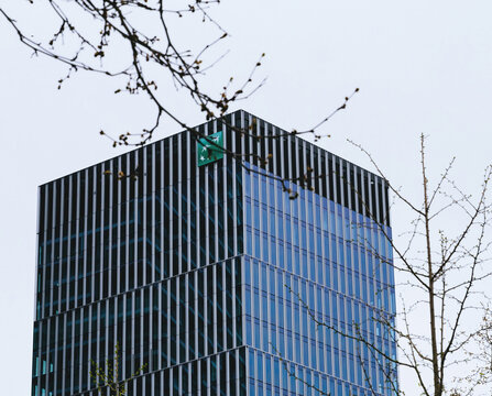 Frankfurt, Germany - Mar 31, 2024: Low-angle view of BNP Paribas bank HQ in Frankfurt, peeking through spring branches, symbolizing growth and stability