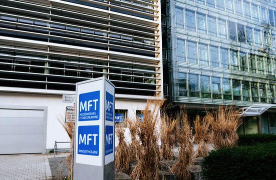 Frankfurt, Germany - Mar 31, 2024: A signpost for MFT Medizinisches Fitnesstraining and physiotherapy outside a modern building amidst urban greenery in Frankfurt