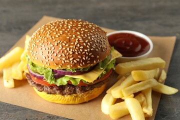 Burger with delicious patty, french fries and sauce on table, closeup
