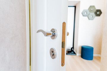 Door lock on white door, door locking mechanism, apartment interior, private hallway house.