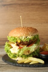 Burger with delicious patty, french fries and sauce on wooden table