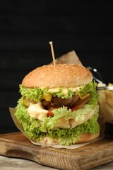 Burger with delicious patty on wooden table against dark background