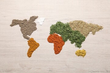 World map of different spices on wooden table, flat lay