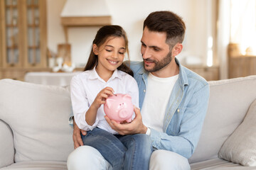 Father and daughter saving money together at home