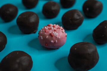 Closeup of delicious chocolate cake balls with a pink one in the middle on a blue background