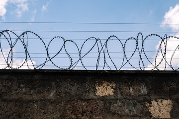 Concrete block wall with barbed wire at a protected area. Security, detention center, concentration...