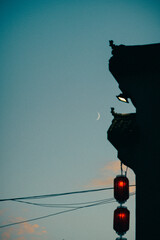 Beautiful view of a crescent moon in a blue sky and traffic lights in a foreground