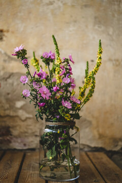 Fototapeta Fresh purple flowers in glass jar on wooden table against wall