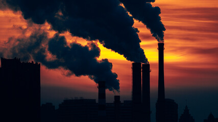Industrial factory with smoke at sunset - concept of air pollution