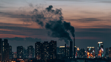 Obraz premium Industrial factory with smoke and modern buildings at sunset