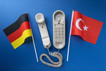 Flag of Germany, Turkey and old corded telephone on a blue background, concept on the theme of...